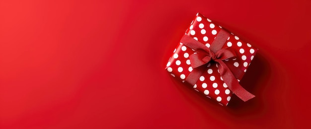 Photo red gift box with white polka dots and red ribbon on red background