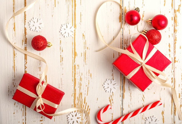 Red gift boxes, Christmas toy, fir branches, christmas candy, on the white wooden background.