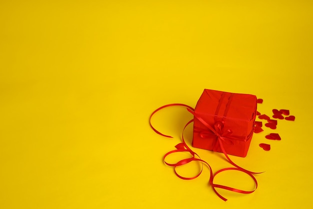 A red gift and hearts on a yellow background Picture for Valentines Day The 14th of February