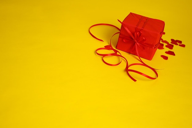 A red gift and hearts on a yellow background Picture for Valentines Day The 14th of February