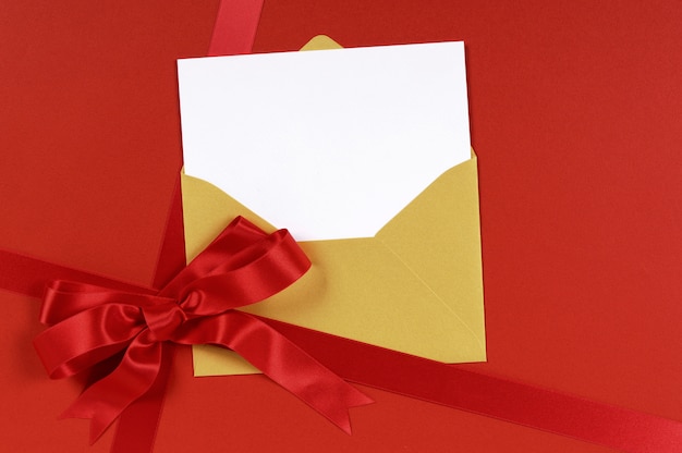 Red gift with gold envelope and blank invitation or greetings card.