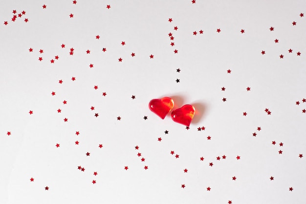 red glass hearts on white with confetti.