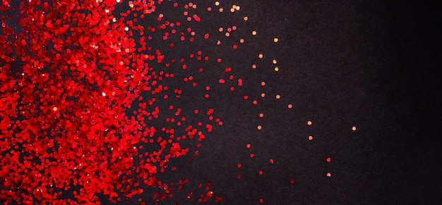 Red glitter on black paper background with copy space