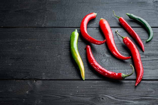 Red and green chili pepper set, on black wooden table background , with copyspace  and space for text