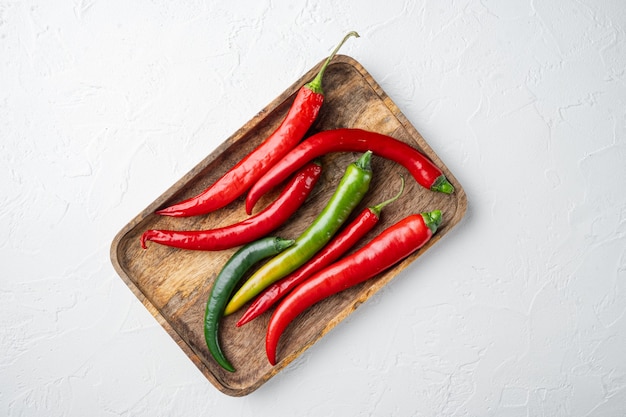 Red and green chili pepper set, on wooden tray, on white