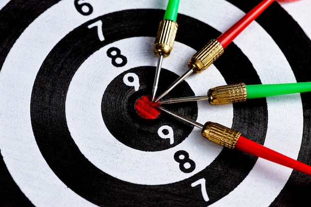 Red and green dart arrow hitting target center is Dart board Isolated on black surface