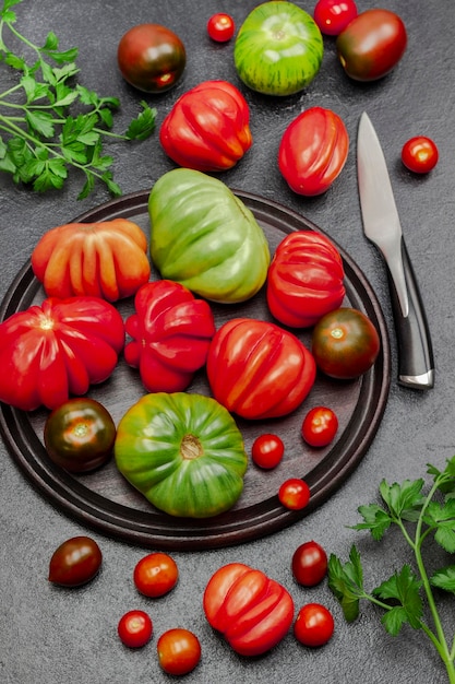 Red and green tomatoes on cutting board and on table Parsley sprigs and knife