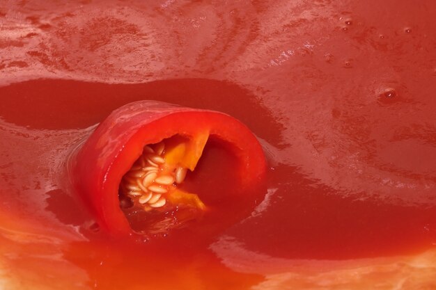 Red grocery background of tomato juice with sweet pepper splash close-up