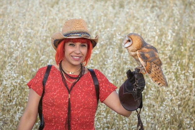 Photo red hair woman with a white owl on her arm