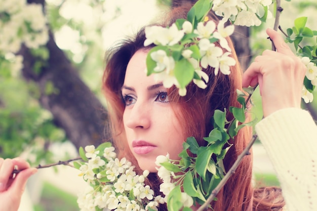 Red hair women in apple flower branch