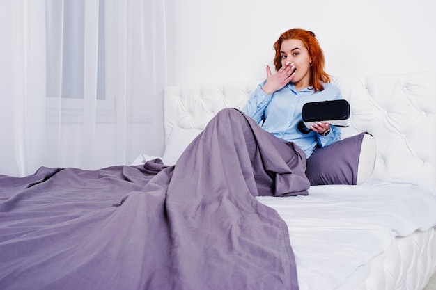 Red haired girl in bed with vr glasses at studio room