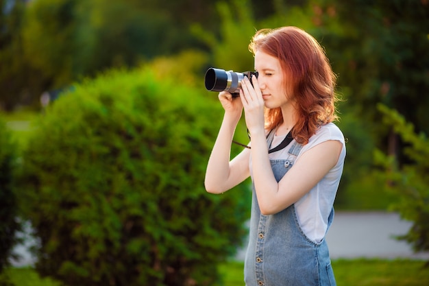 Red-haired girl photographer in the Park