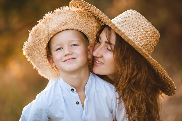 Red-haired girl with a child against the backdrop of a sunset. Cute mother with a blond baby