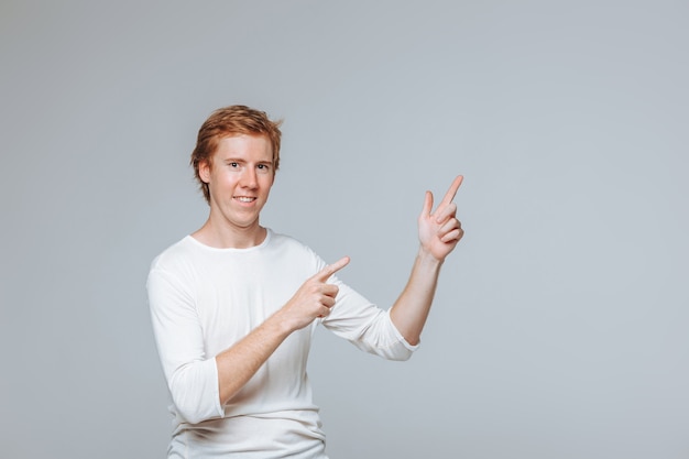 red haired man on a light background points