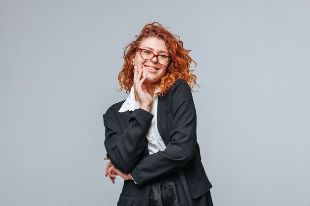 Red-haired woman in a black jacket and glasses smiling