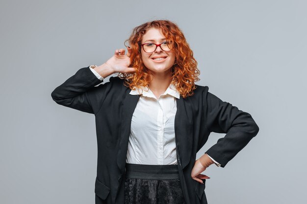 Red-haired woman in a black jacket and glasses smiling