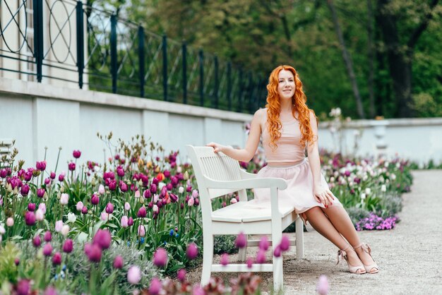 Red-haired young woman walking in a park with big white mansion