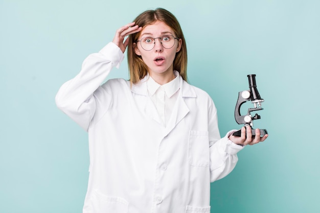 Red head pretty woman looking happy astonished and surprised scientist with microscope concept