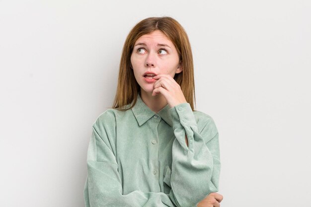 Red head pretty woman with surprised nervous worried or frightened look looking to the side towards copy space