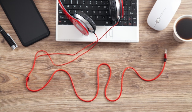 Red headphones coffee computer keyboard and other objects on the wooden desk