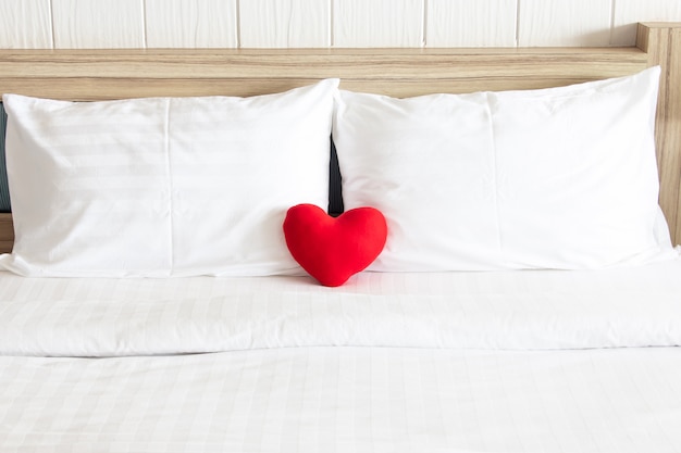 Red heart and Couple white pillow on the bed for love, wedding and valentine's day concept