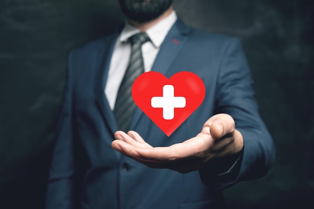 Red heart and cross Medicine concept Man holding in his hand