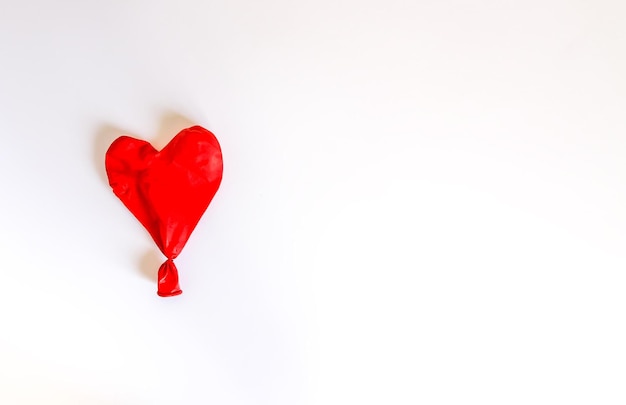 Red heart deflated balloon on white background.