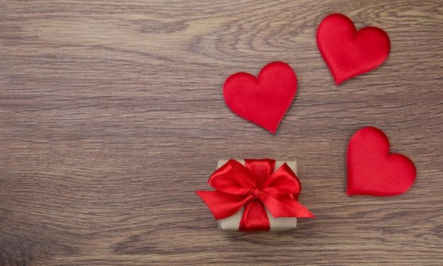 A red heart and a gift on a wooden backgroundThe concept of love family health charity