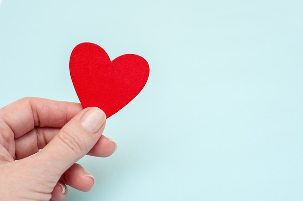 Red heart in hand on blue background