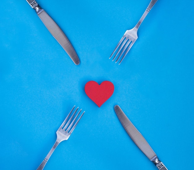 Red heart knife and fork on the blue backgroundTop viewCopy space