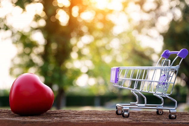 Red Heart Shape On Mini Shopping Cart Over Nature Background