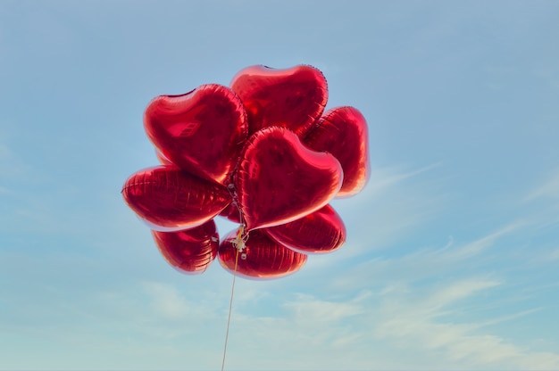 Red heart-shaped balloons with blue sky in vintage style, concept of love and valentine. Love is in the air