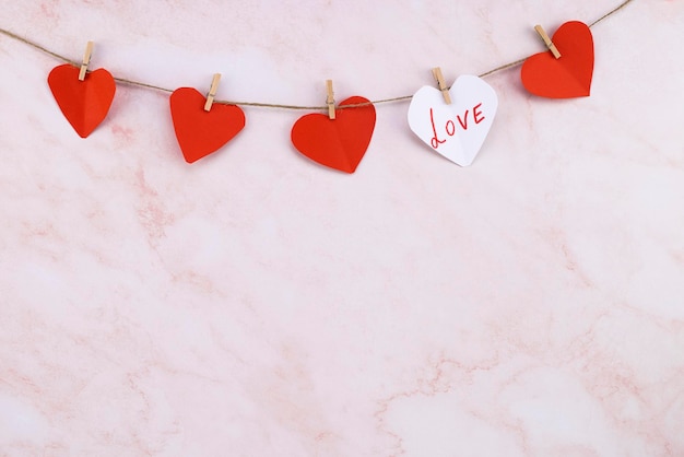 Red heart shaped garland on over pink wall background Valentines Day garland