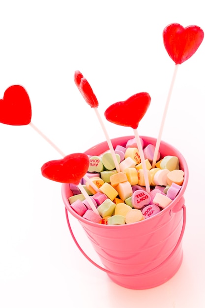 Red heart shaped strawberry lollipops in pink bucket.