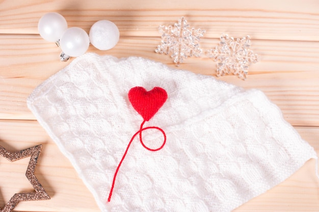 Red heart on a white knitted background with a fir twig New Year's background