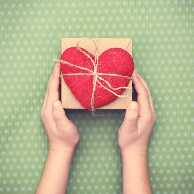 Red heart with a gift box to Valentine's Day on a beautiful green