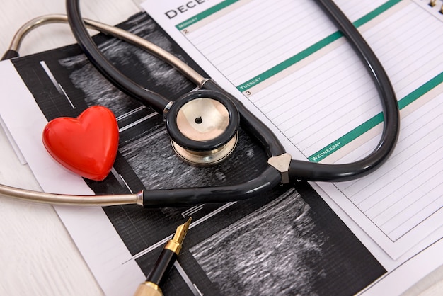 Red heart with stethoscope and analysis results on table