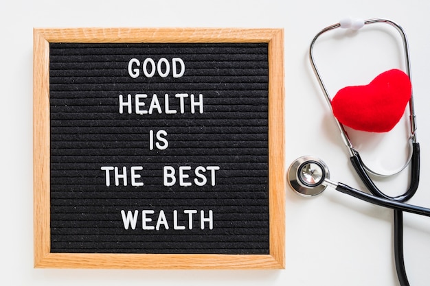 Photo red heart with stethoscope and notice board with good health message on white background