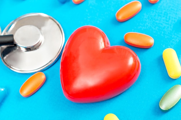 Red heart with stethoscope and pills on a blue background Close up Medical concept