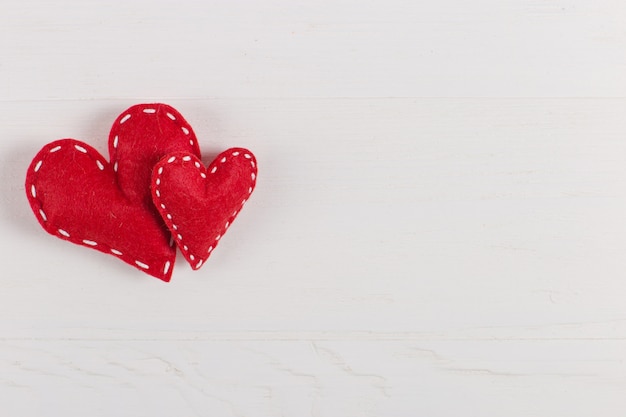 Red hearts are handmade on white background. Preparation for Valentine's Day with a place for text. Copy space.