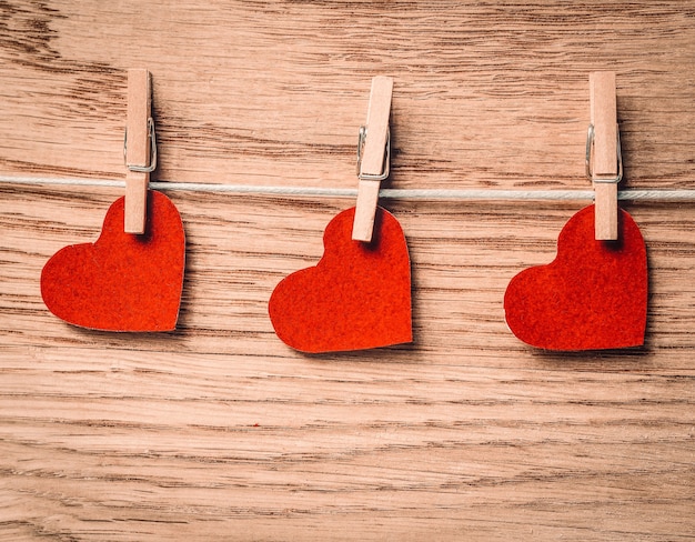 Red hearts on clothespins on wooden background . photo with copy space