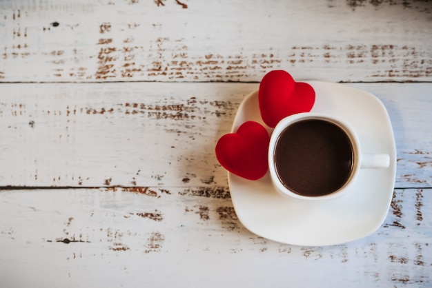 Red hearts and a Cup of coffee on a white wooden background