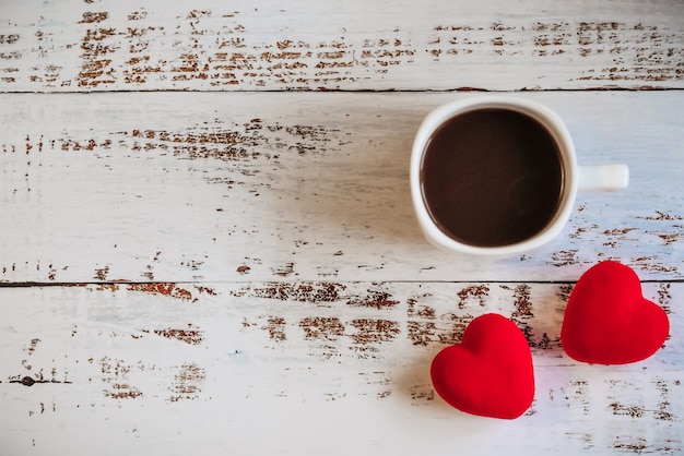 Red hearts and a Cup of coffee on a white wooden background.