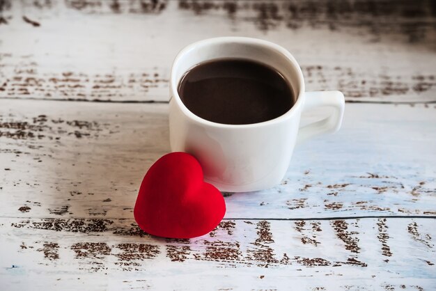 Red hearts and a Cup of coffee on a white wooden background.