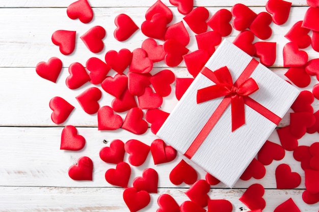 Red hearts and gift box on white wood