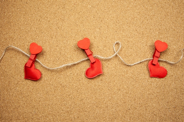 Red hearts with clothespins on corkboard, strong love concept