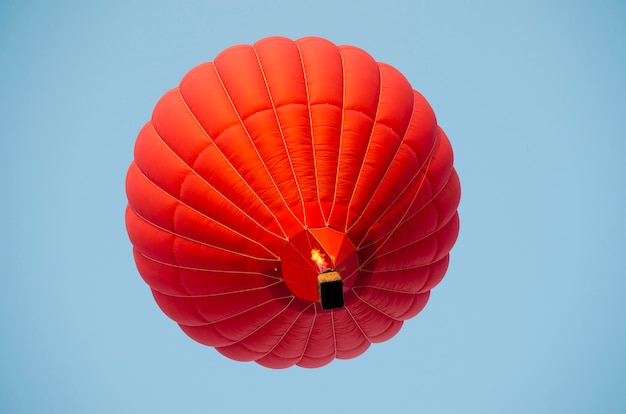 Red hot air balloon in a clear blue sky.