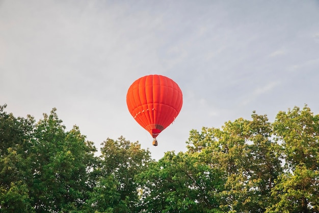 Red hot air balloon flying in the sky at sunset