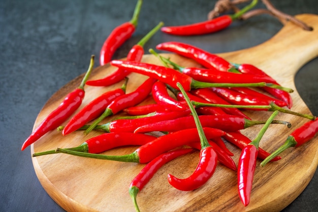 Red Hot Pepper Chili Peppers on a cutting wooden board vintage stone background