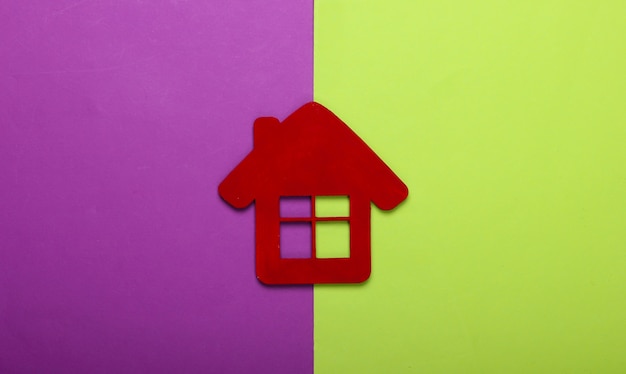 Red house figurine on purple green background. Top view